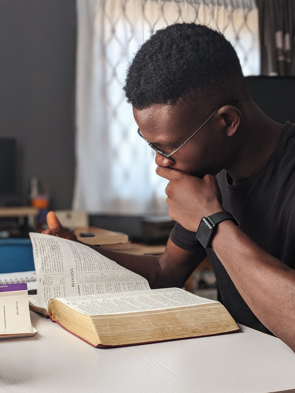 man wearing black crew neck shirt reading book